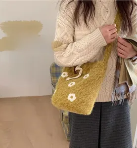 Detail of mustard yellow plush bucket bag with 3D white flowers and wide strap
