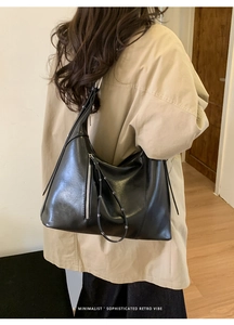 Detail of minimalist black retro hobo bag with sleek silver zipper and leather texture