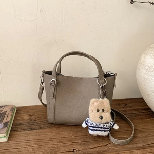 Detail of dark grey litchi grain bucket bag with detachable strap and cute bear charm
