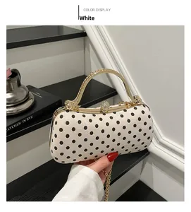 Close-up of elegant polka dot box bag with gold metal handle and rhinestone clasp