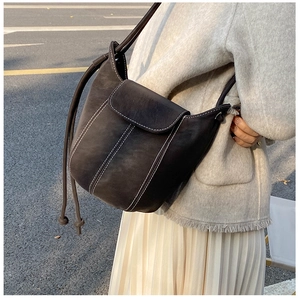 Close-up of vintage brown leather bucket bag featuring white contrast stitching details