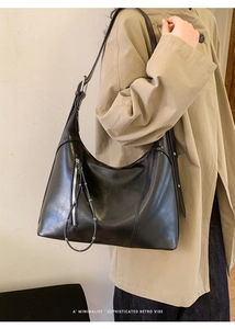 Close-up of a minimalist black polished leather tote bag with vertical zipper detail