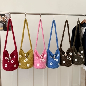 Detail view of colorful knitted shoulder bags with floral patterns and horn buttons