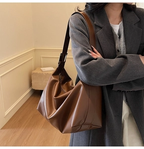 Detail of adjustable metal buckle and pleated texture on brown faux leather tote bag