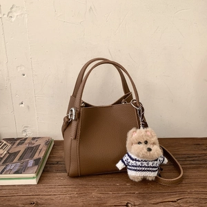 Brown litchi grain leather bucket bag featuring a cute plush dog pendant and silver hardware