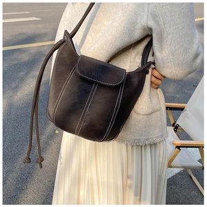 Detail of dark brown vintage bucket bag with contrast white stitching and flap closure