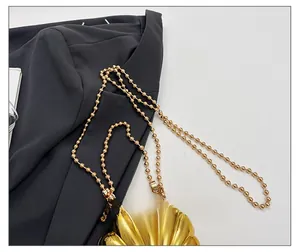 Close-up of a golden shell-shaped mini bag with textured surface and elegant ball chain strap