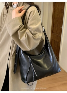 Detail of the black leather shoulder bag with metallic buckle and retro minimalist design