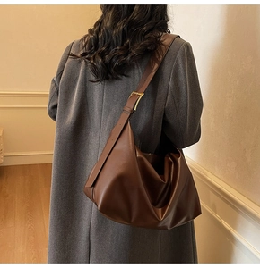 Detail of dark brown leather tote bag with gold metal buckle on a shoulder strap