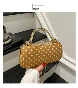 Close-up of brown polka dot suede clutch with gold chain handle and rhinestone clasp