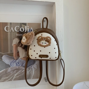 Detailed shot of a polka dot mini backpack with a plush bear patch and matching charm