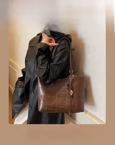 Detail of dark brown faux crocodile tote bag with gold logo and bead charm detail