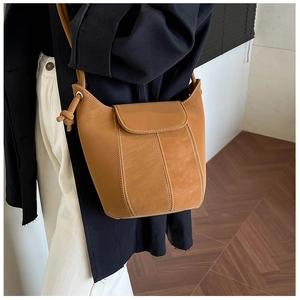 Close-up of vintage brown bucket bag with white contrast stitching and side knot detail