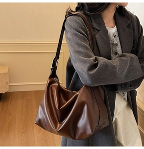 Detail of adjustable strap with gold-tone buckle on dark brown oversized tote bag