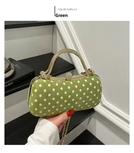 Detailed view of green suede evening bag with white polka dots and golden U-handle
