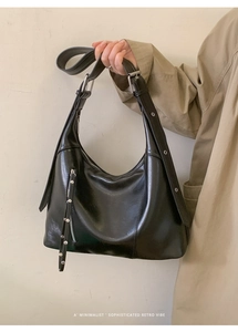 Detail of black leather hobo bag with silver buckle and adjustable shoulder strap