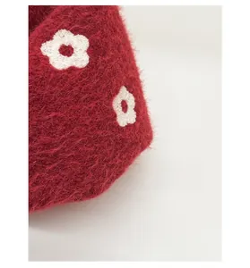 Detailed close-up of red faux mink fabric with white embroidered floral patterns