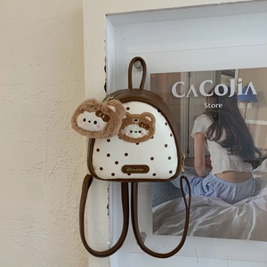 Detailed view of mini white polka dot backpack with brown plush bear charms and logo