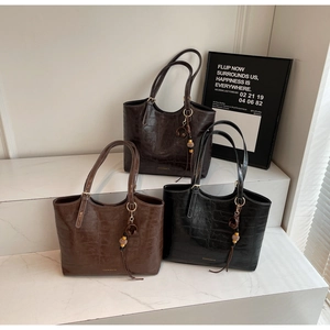 Three crocodile embossed tote bags in brown, dark coffee and black on marble steps
