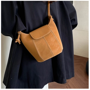 Brown leather bucket bag with white contrast stitching detail worn by a model
