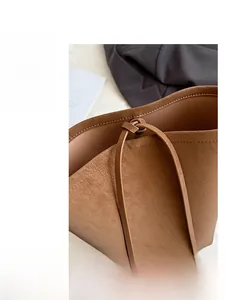 Macro detail of brown leather tote bag with lychee grain texture and drawstring closure