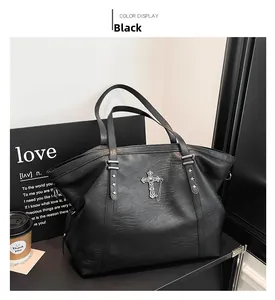Close-up of black leather tote bag featuring a metal cross and silver star rivets