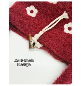 Detail of burgundy plush handbag featuring white flower pattern and toggle closure