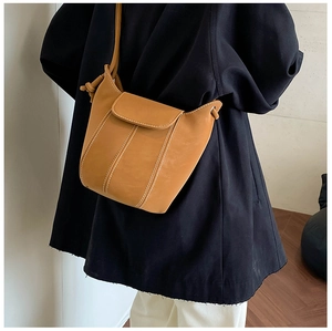 Detail of camel bucket bag featuring white contrast stitching and unique curved opening