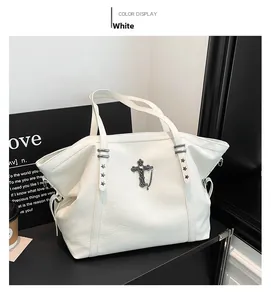 Detail view of white tote bag featuring a vintage cross pendant and star studs decorations