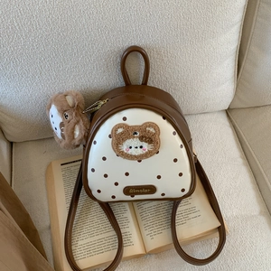 Mini brown polka dot backpack with plush bear detail on open book pages