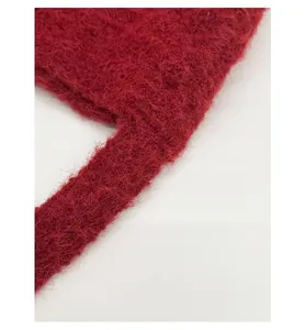 Detail of reinforced shoulder strap on plush red handbag with soft fluffy texture
