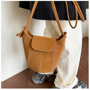 Close-up of vintage camel leather bucket bag with white contrast stitching and slim strap