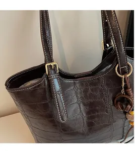 Detail of dark brown faux crocodile tote bag with gold hardware and white stitching
