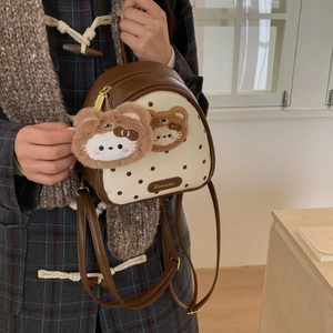 Detail of mini polka dot handbag with cartoon bear embroidery and plush charm accessory
