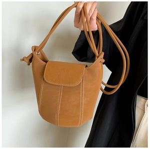 Detail of tan bucket bag featuring white contrast stitching and smooth faux leather