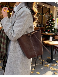 Détail du sac seau en daim marron foncé avec cordon de serrage dans un décor automnal