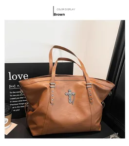 Detailed view of brown tote bag with gothic silver cross charm and star studs accent