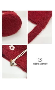 Detail of burgundy plush knit drawstring bag with white flower embroidery and soft texture