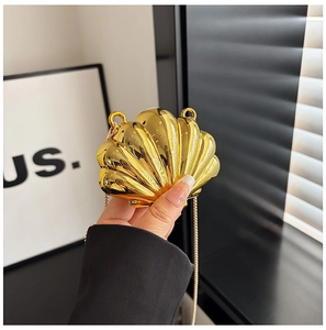 Macro shot of a shiny gold shell-shaped mini bag with a refined metal chain strap