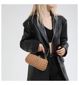 Polka dot box bag with gold chain strap shown on a black leather jacket model