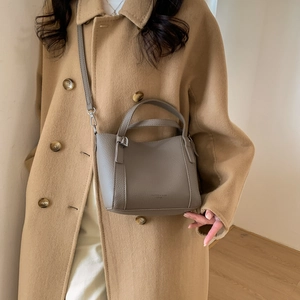 Detailed view of grey lychee leather bucket bag with silver buckles and handle strap