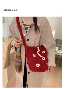 Detail of red plush drawstring bag with white 3D flower accents and soft fur texture