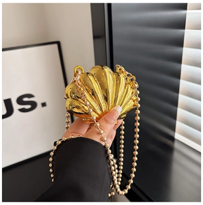 Macro view of shell-shaped gold evening bag with high-polish metallic texture and bead chain