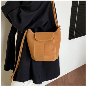 Close-up of caramel vintage bucket bag with contrast white stitching and flap closure