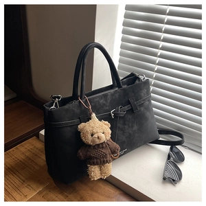 Detail of black suede tote bag with a cute bear charm and fashion decorative buckle