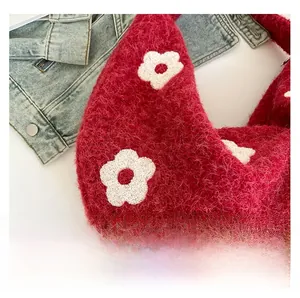 Détail de la texture d'un sac bandoulière rouge en fausse fourrure avec fleurs blanches
