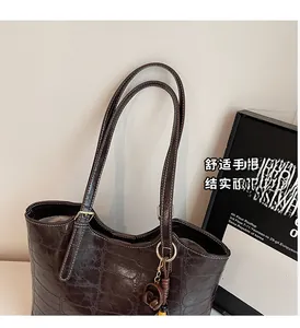 Detail of dark brown faux crocodile tote bag with long straps and large capacity