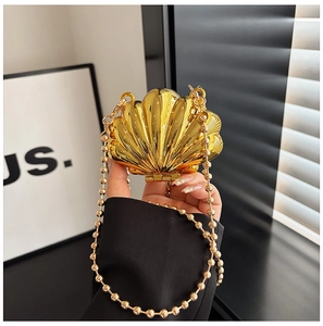 Detail of a gold shell-shaped clutch bag with luxury pleated metal texture and pearl chain