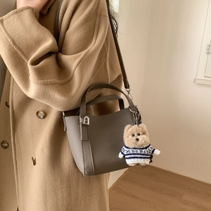 Detail of grey pebbled leather bucket bag featuring a cute teddy bear charm pendant