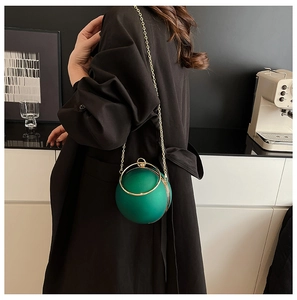 Detail of green acrylic ball bag featuring a gold ring handle and metal chain strap